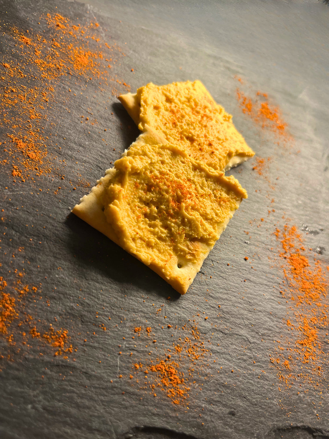 Serveer bord met toastjes besmeerd met hummus van paprika poeder, tomaat passata, kikkererwten, op een lijstenen bord 