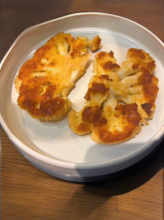 Serveerdbord op houten tafel met krokant gebakken bloemkool, vega snitzel