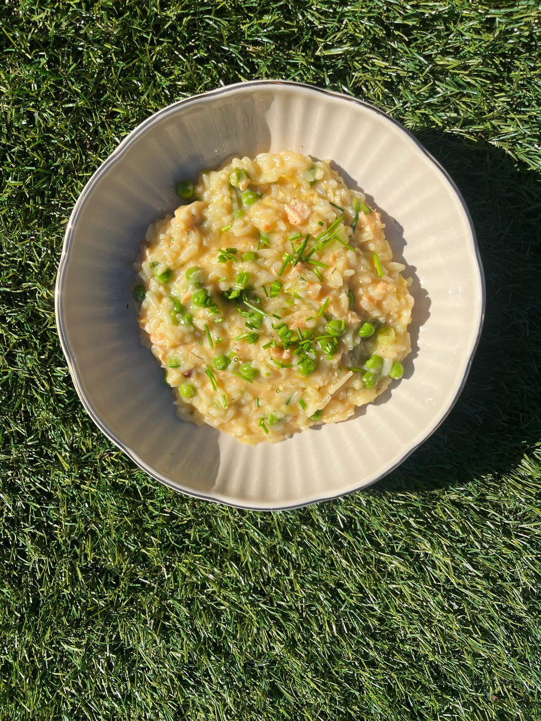 Mooi bord waarop risotto is gepresenteerd, incombinatie met witvis, gerookte zalm en doperwten