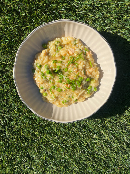 Mooi bord waarop risotto is gepresenteerd, incombinatie met witvis, gerookte zalm en doperwten